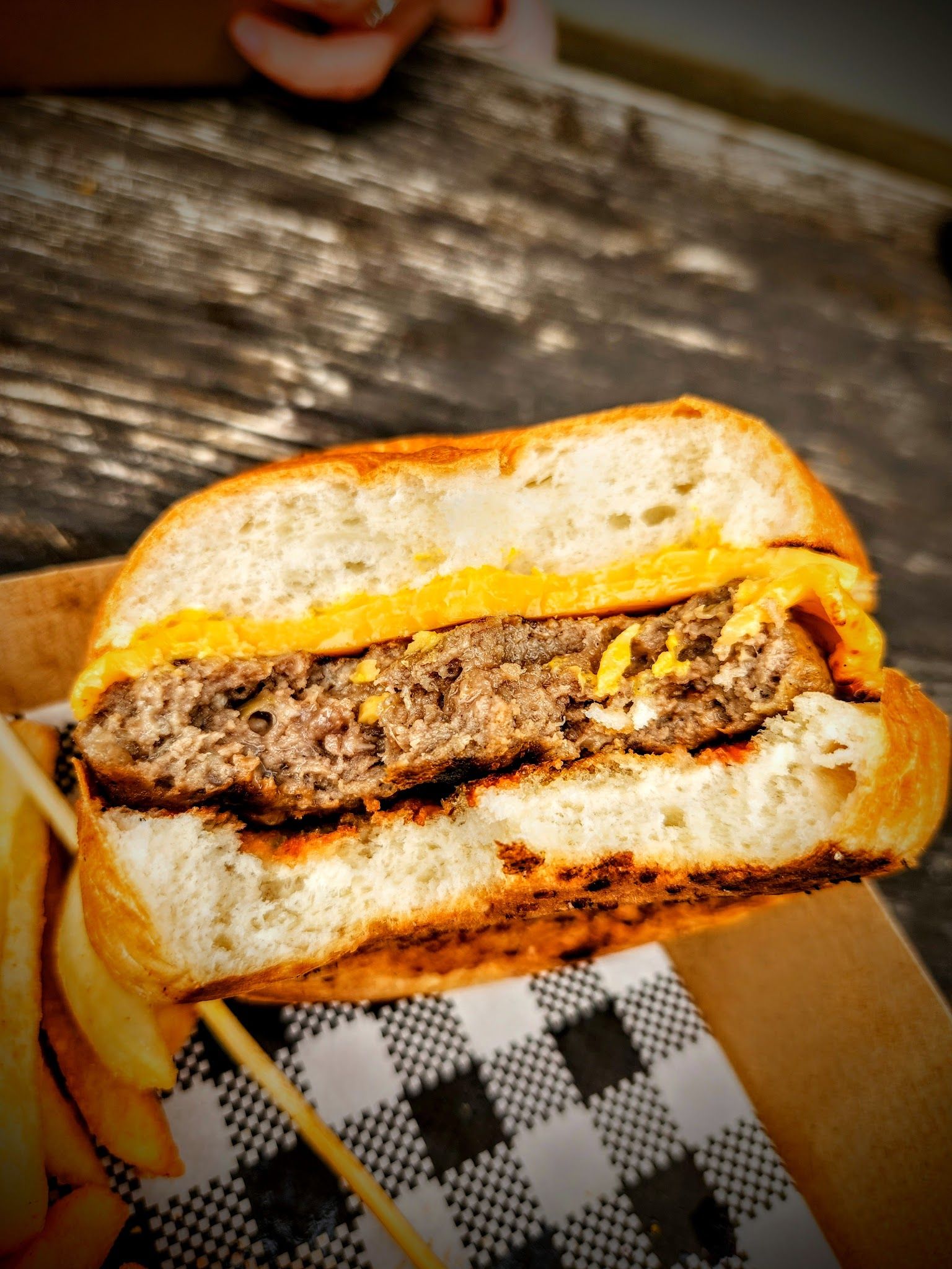 Burger cut in half showing beef patty and melted cheese, photographed outdoors