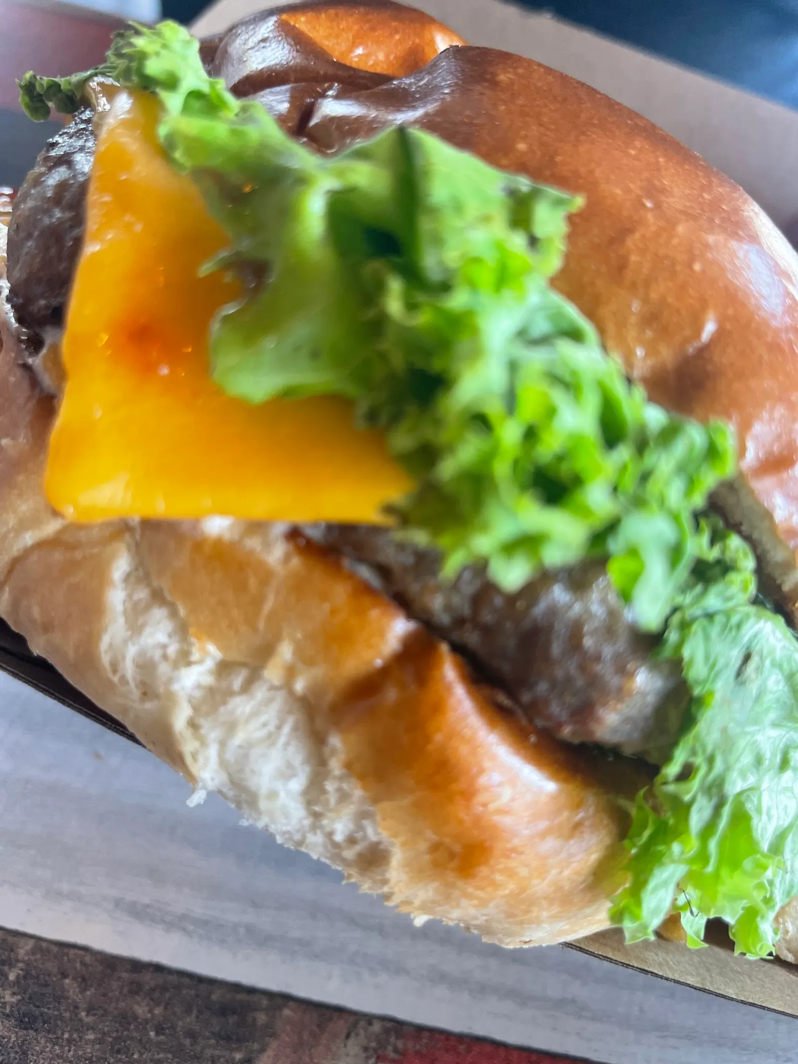 Close-up of a cheeseburger with melted cheese and green lettuce on a brioche bun